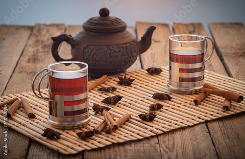 Bowl of dried dates and other spices on old wooden table with tea in glasses.