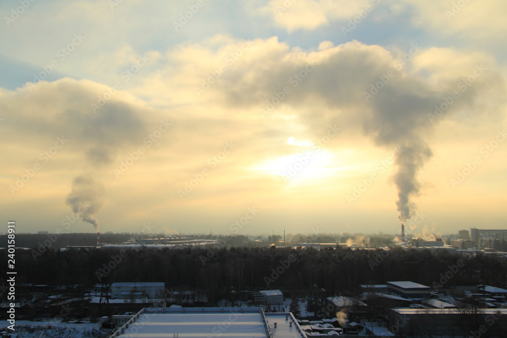 Cityscape with smoking chimneys of factories at sunset. Industry.