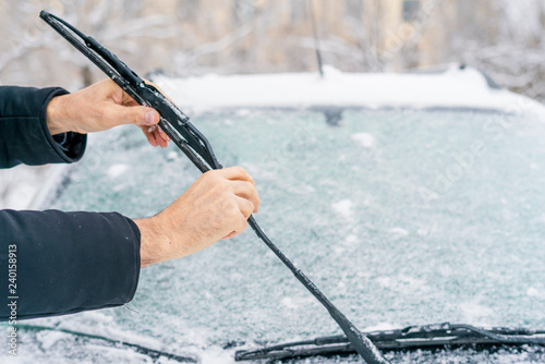 Canvas Print man adjusting and cleaning wipers of car in snowy weather b