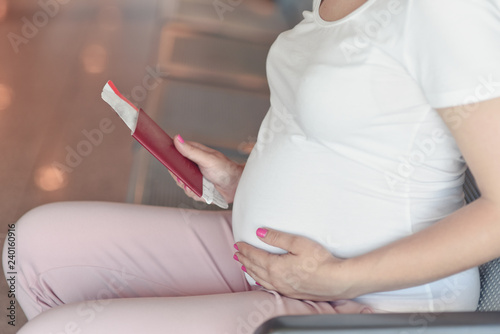 Pregnant woman is traveling by plane sitting at seat.