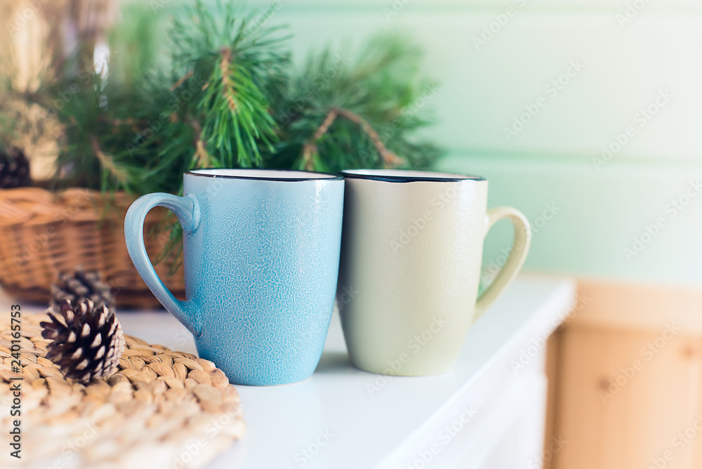 Morning interior. Two cups with a drink and a bouquet of pine needles on a white table in the morning Sunny day.