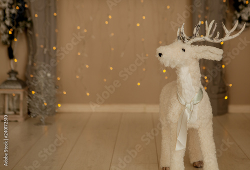 Christmas decoration, a white deer representation figurine on red garlands and Christmas lights background