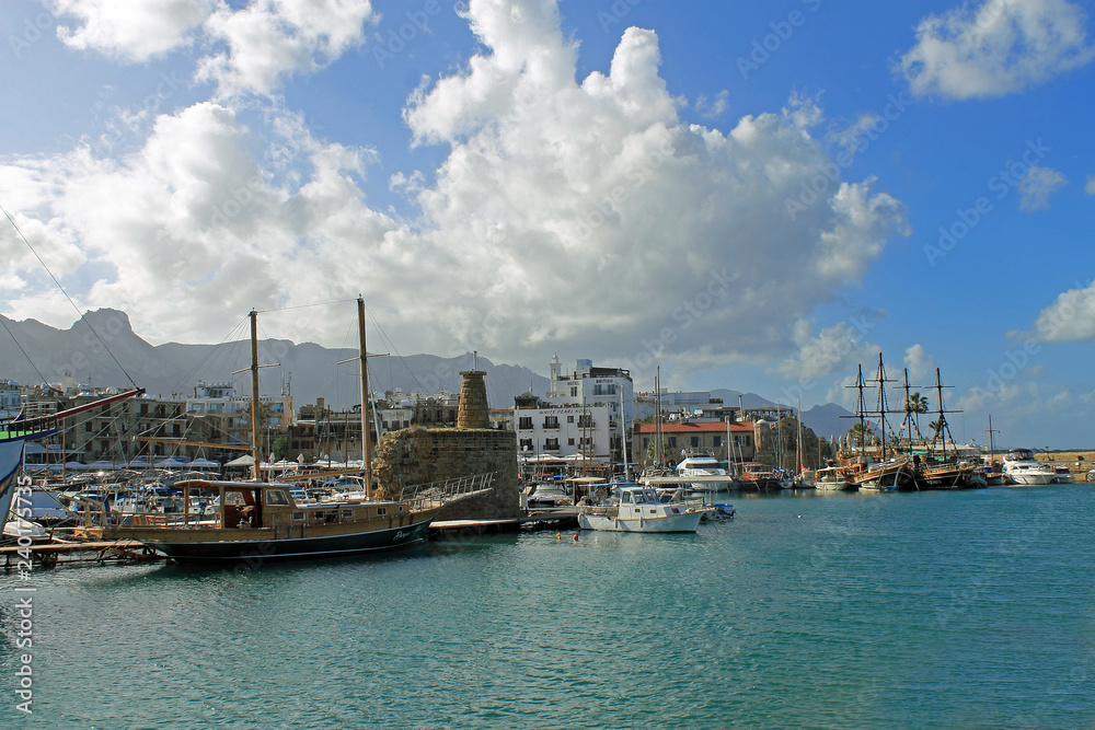 Alte Hafenanlage von Kyrenia im Norden von Zypern, mit alten Segelschiffen unter Schönwetterwolken am blauen Himmel
