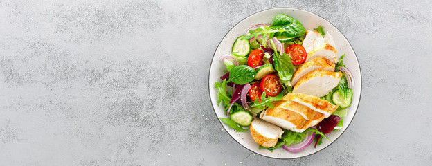 Grilled chicken breast, fillet and fresh vegetable salad of lettuce, arugula, spinach, cucumber and tomato. Healthy lunch menu. Diet food. Top view. Banner