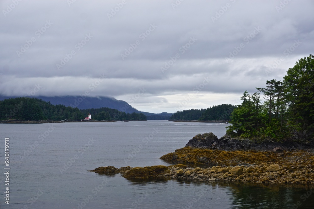 Sitka, Alaska, USA: A small lighthouse on an island in the waters off of Sitka, Alaska, under a cloudy sky.