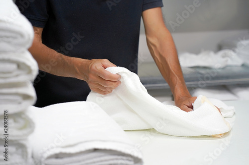 Фотография Hands of caucasian male laundry hotel worker folds a clean white towel