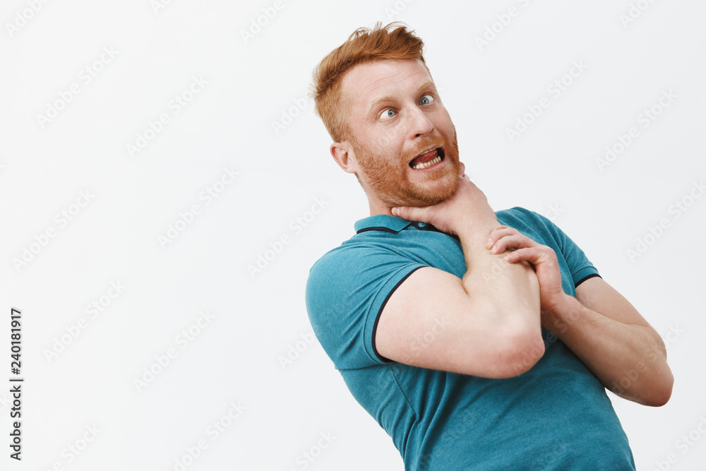 It is gonna chuckle me. Portrait of funny carefree and playful redhead guy with bristle, bending backwards while holding himself on neck, choking for fun, sticking out tongue and squinting It is gonna chuckle me. Portrait of funny carefree and playful redhead guy with bristle, bending backwards while holding himself on neck, choking for fun, sticking out tongue and squinting