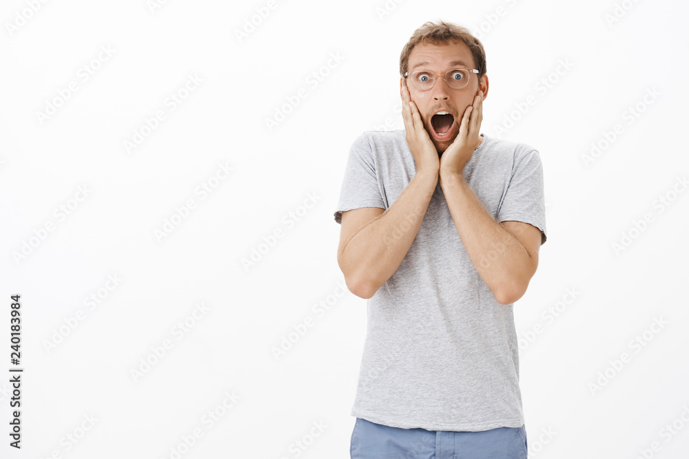 Omg awesome news. Portrait of impressed and amazed speechless emotive handsome guy in transparent glasses with bristle dropping jaw and gasping holding hands on face from astonishment Omg awesome news. Portrait of impressed and amazed speechless emotive handsome guy in transparent glasses with bristle dropping jaw and gasping holding hands on face from astonishment