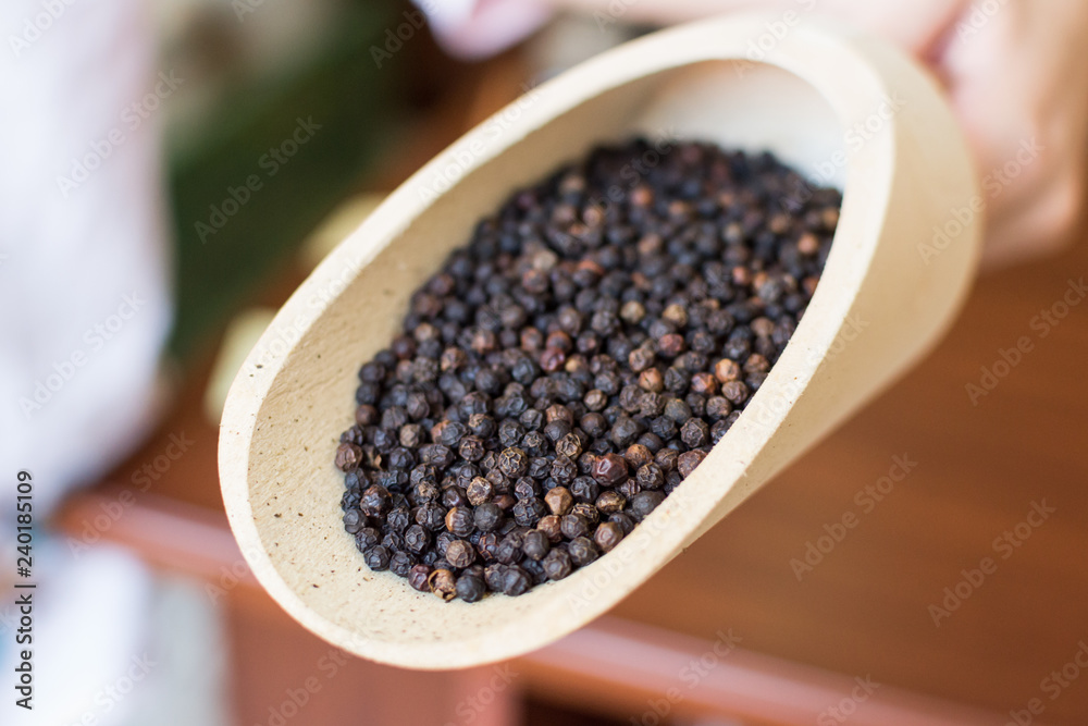 Black peppercorns closeup in wooden scoop Black peppercorns closeup in wooden scoop