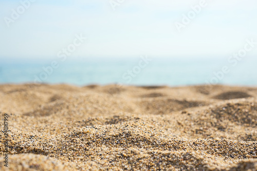 Sand on the beach close up with blurred sea and waves on a background.