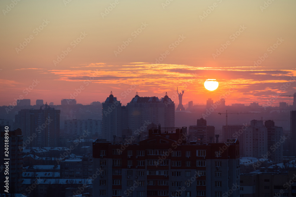 Fototapeta premium Sunset in Kiev, evening view of the panorama of the city, the church and the statue of the Motherland. Evening color urban landscape