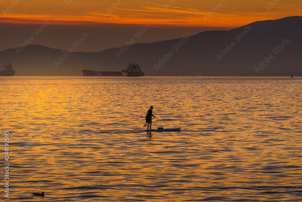 woman on paddlebard at sunset