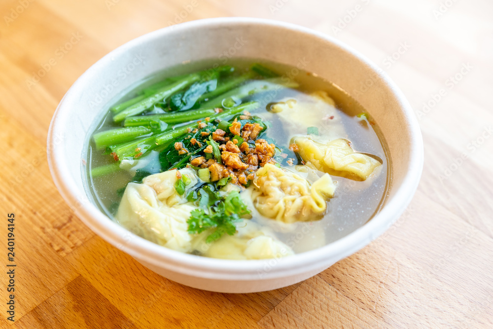 Top view of Wanton soup with morning glory and deep fried garlic in bio paper bowl on wooden background. Top view of Wanton soup with morning glory and deep fried garlic in bio paper bowl on wooden background.
