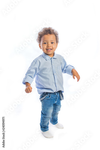 Little black kid with curly hair stand with arms spread to the side and smiling at camera, isolated background