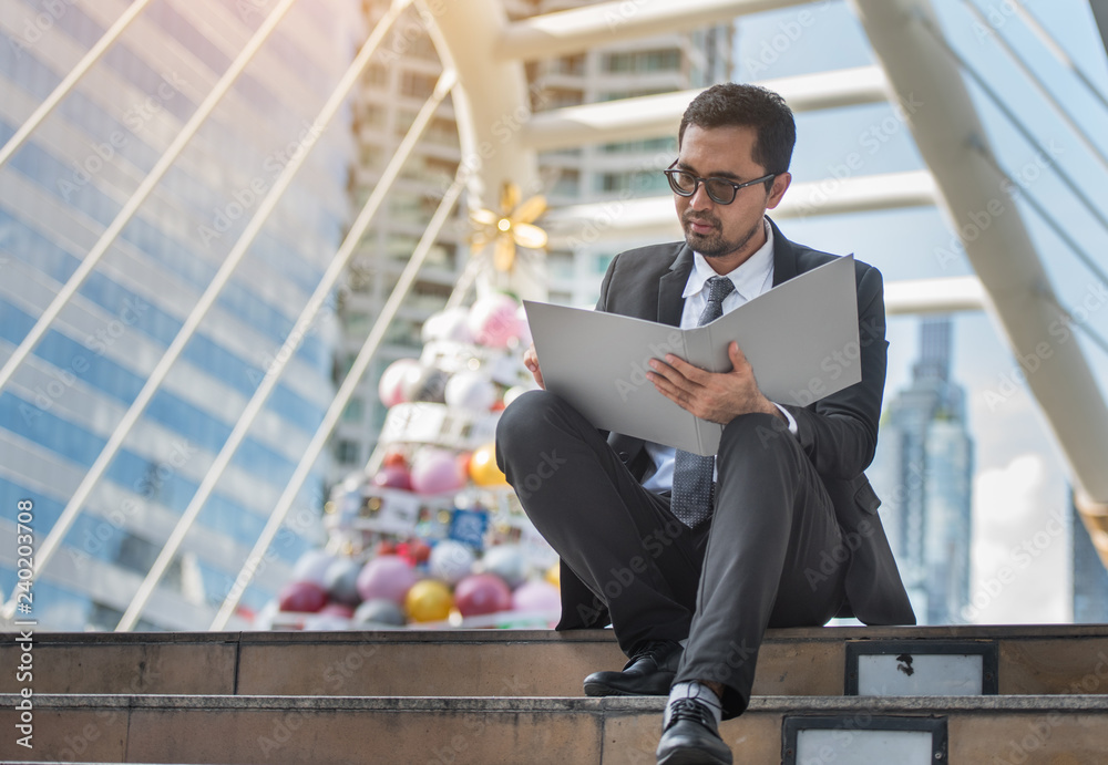 Businessman looking at the Document file in his hand on the BTS station Businessman looking at the Document file in his hand on the BTS station