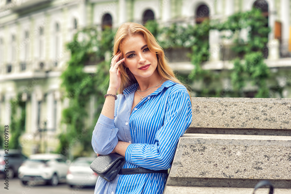 Fototapeta premium Young beautiful woman in dress on summer city street