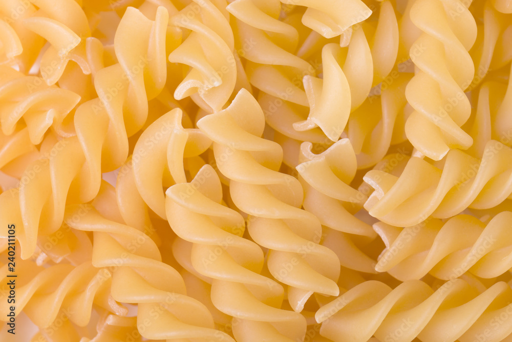 Raw fusilli pasta uncooked closeup. Food background. Top view Raw fusilli pasta uncooked closeup. Food background. Top view
