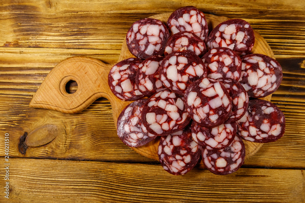 Sliced salami sausage on cutting board on wooden table. Top view Sliced salami sausage on cutting board on wooden table. Top view