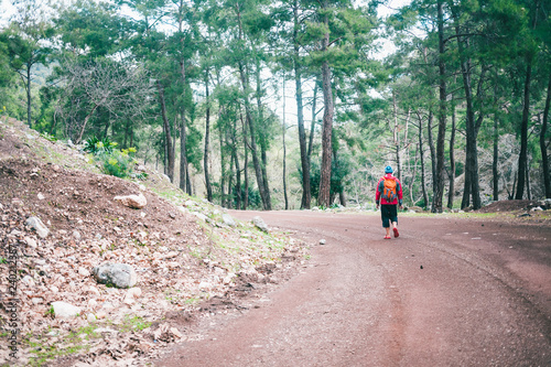 A man with a backpack is on a mountain road