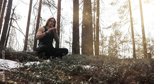 A musician with a tool in nature. A man is playing a flute in a pine forest. The music of the druids in the spring forest.
