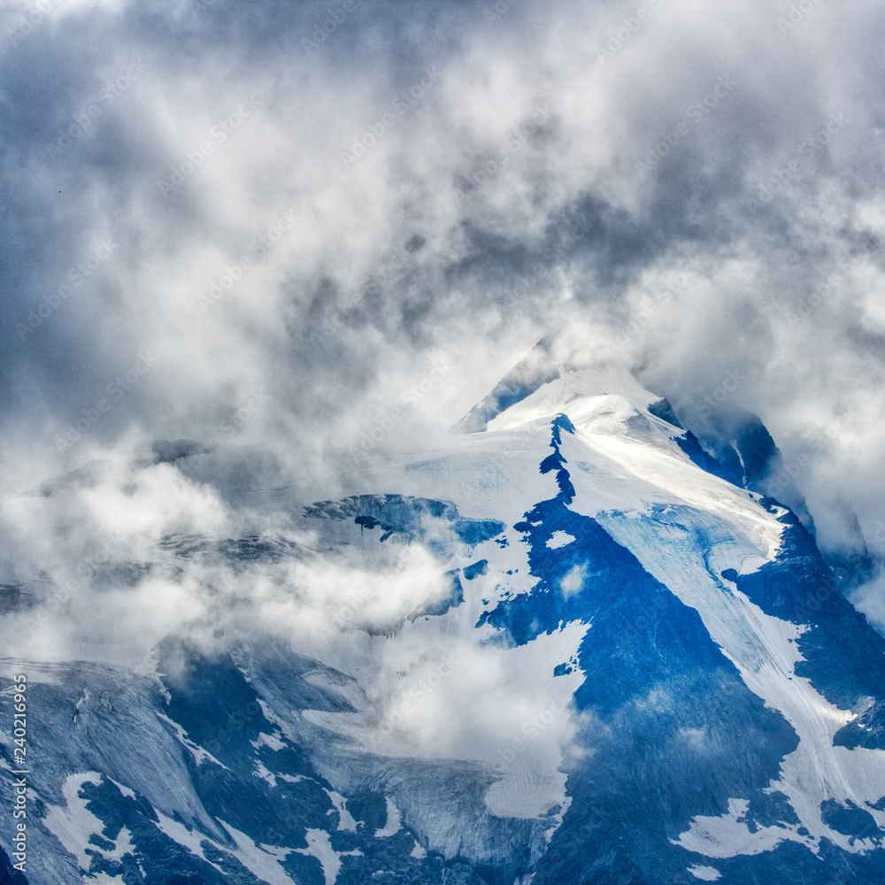 Felsige Berglandschaft mit Wolken, Sonne und Schnee