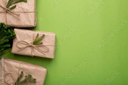 Eco gifts with green plants in craft paper on a green background