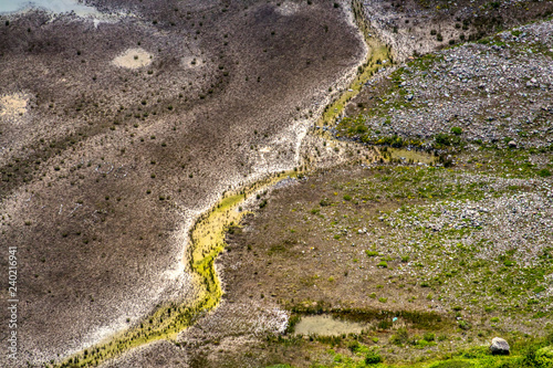 Obraz na płótnie Abstrakte Natur in den Bergen mit grün und braun, vereinzelten Bäumen, Wasser w salonie