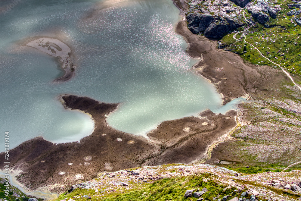 Abstrakter Bergsee mit Wanderweg von oben
