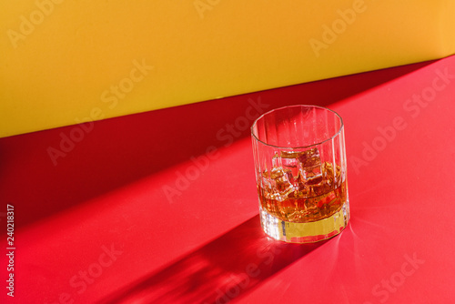 glass of whiskey on red and yellow background solo with copy space