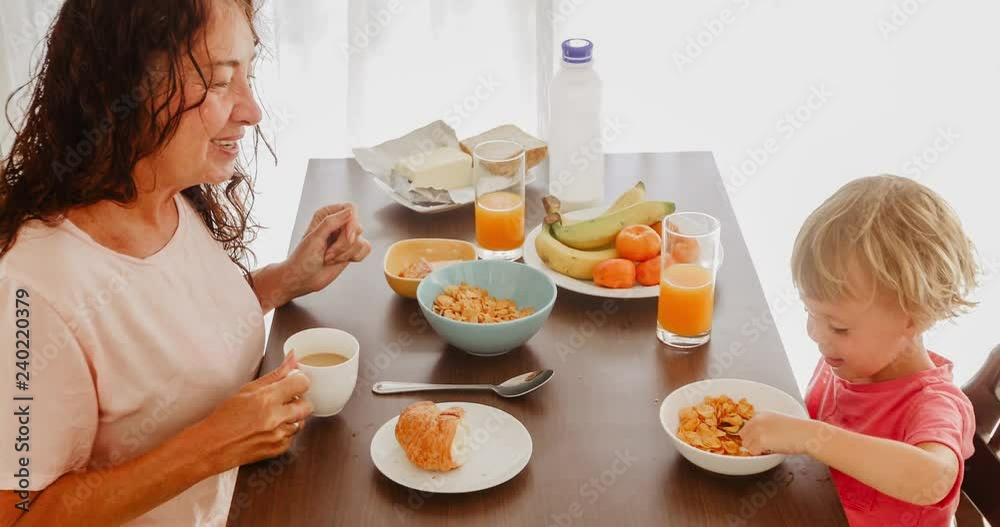 Grandmother and grandson have breakfast in the morning. food, healthy eating, family and people concept Grandmother and grandson have breakfast in the morning. food, healthy eating, family and people concept