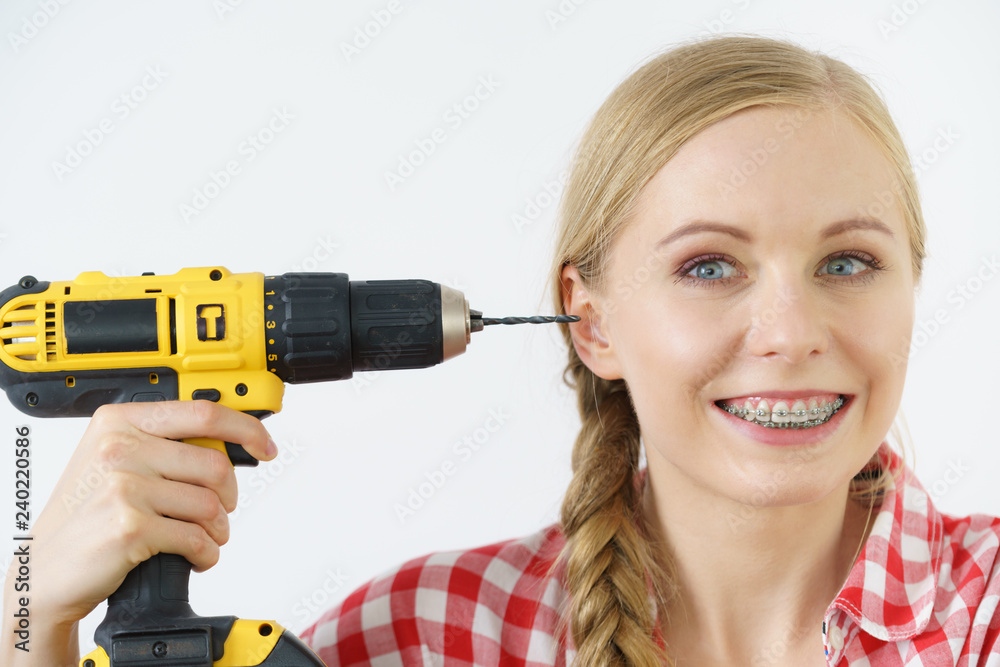 Woman pointing at her head with drill Woman pointing at her head with drill