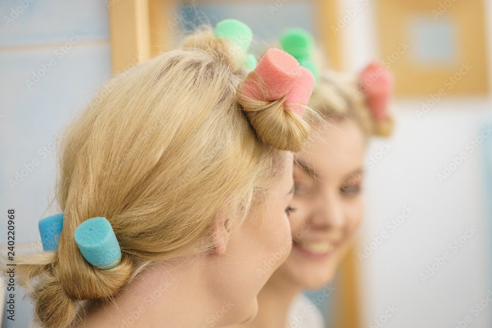 Fototapeta premium Blonde woman using hair rollers