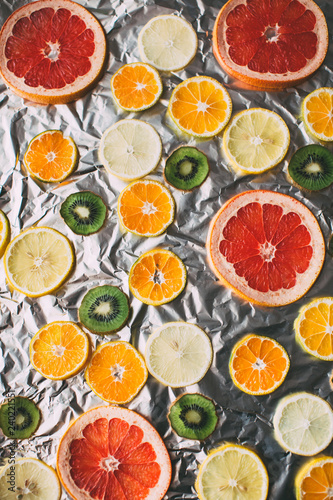 Homemade dried slices of various citrus fruits on a silver background.