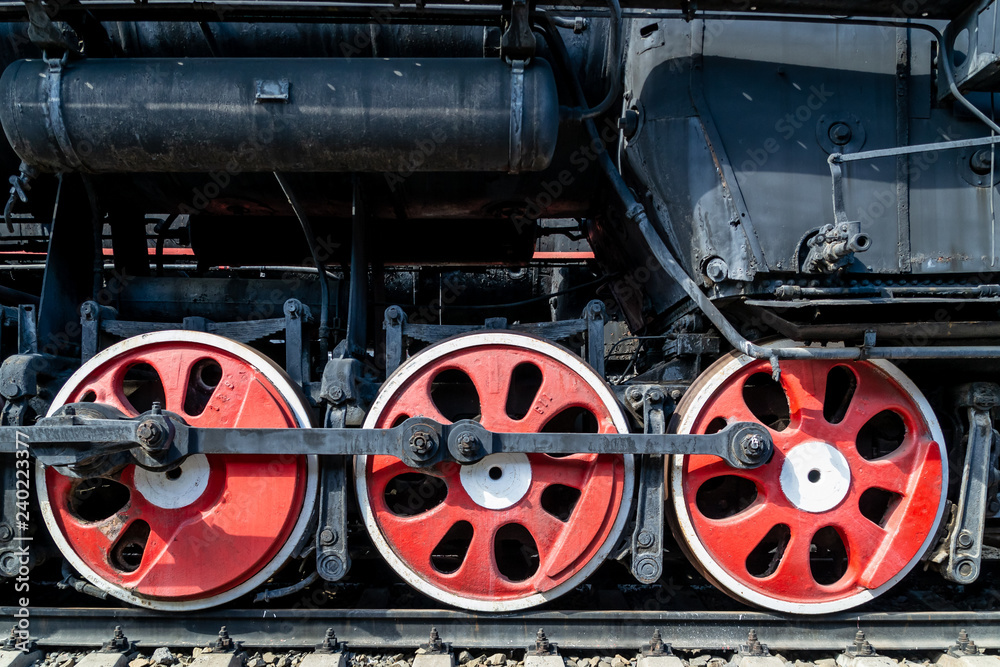 Wheels of the old locomotive of red color and the elements of the drive