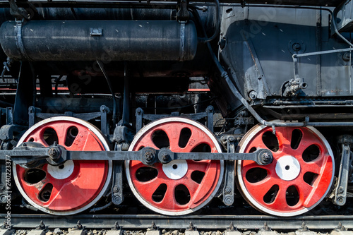 Wheels of the old locomotive of red color and the elements of the drive
