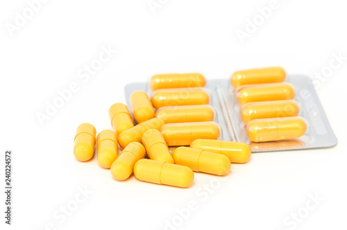 Bright yellow pills and blisters scattered on a white background. Isolated.