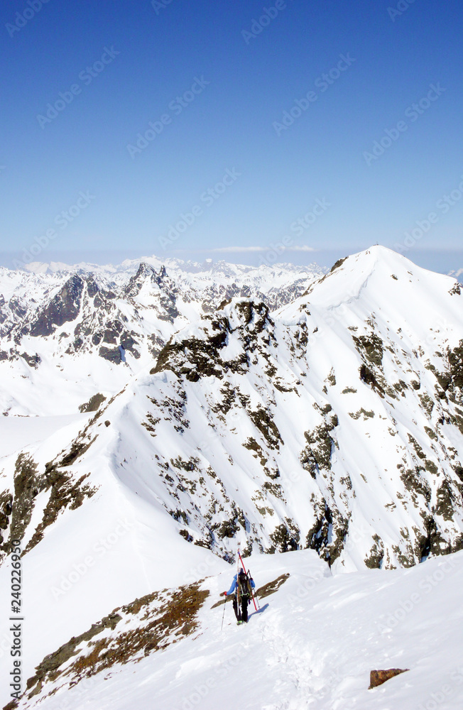 backcountry skier hikes along narrow mountain ridge in the Swiss Alps