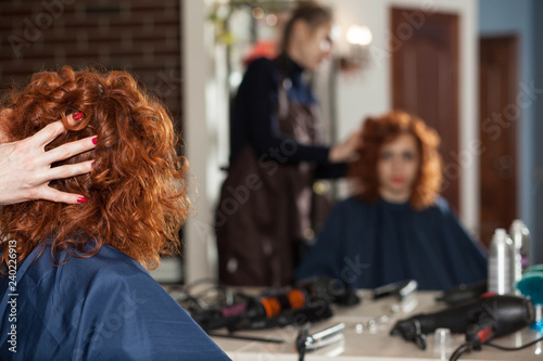The woman in the hairdresser makes a new hairstyle. Reflection in the mirror blurred