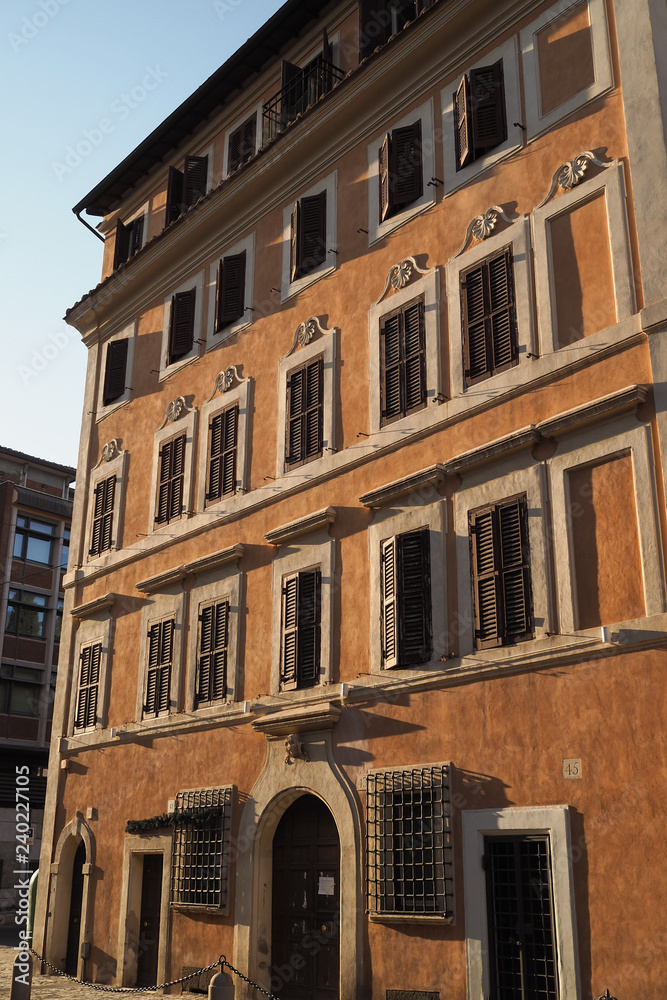 Rome, Italy - building with orange plastered facade, windows and wooden shutters
