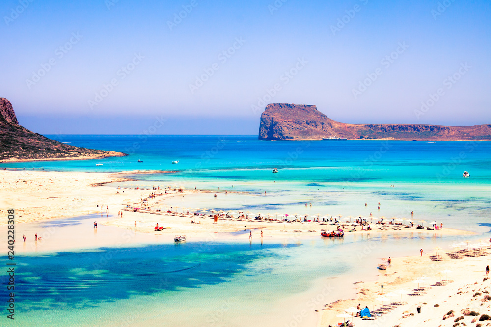 panorama of Balos bay, clay, greece, in summer, white sand, sea and clear blue sky, tropical atmosphere with tourists relaxing in summer