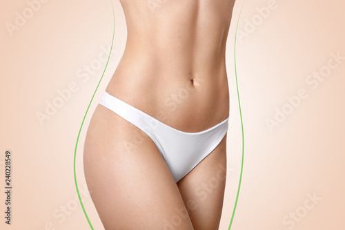 Image of slim womans body shape  has perfect figure  soft skin  green lines  wears white panties  isolated over beige background  has silky legs. Fit nude females belly. Cropped shot of girls torso