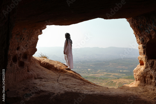 ISOLATED ARABIC MAN WITH DJELLABA AND TURBAN LOOKING TO SUNRISE FROM A CAVE