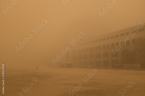 Man walking towards the Mall of the Emirates, which is barely visible, during a sandstorm in Dubai, United Arab Emirates