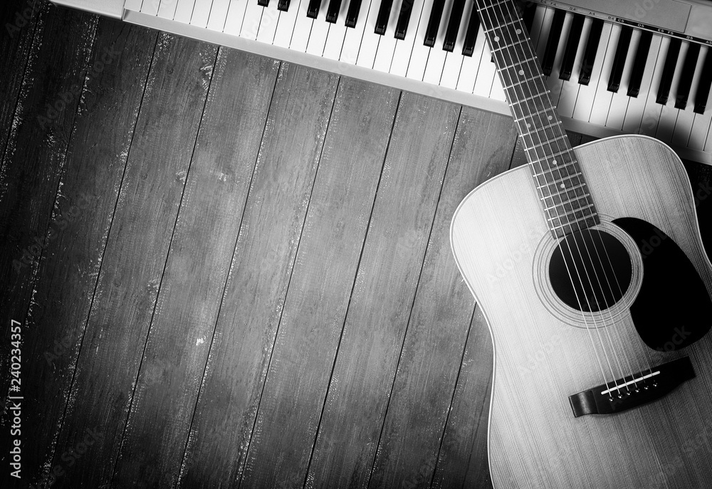 Obraz premium Musical instrument - MIDI keyboard and acoustic guitar wood background monochrome