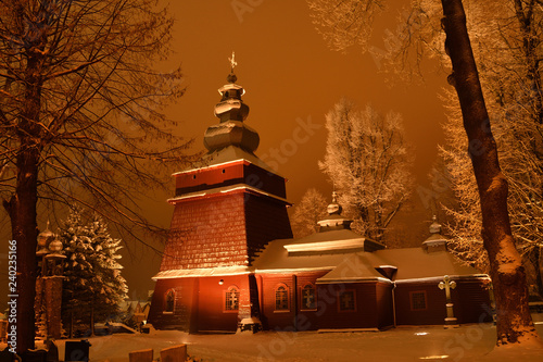 Beautiful illuminated wooden church photography  in the night  winter full of snow Tylicz Poland photo