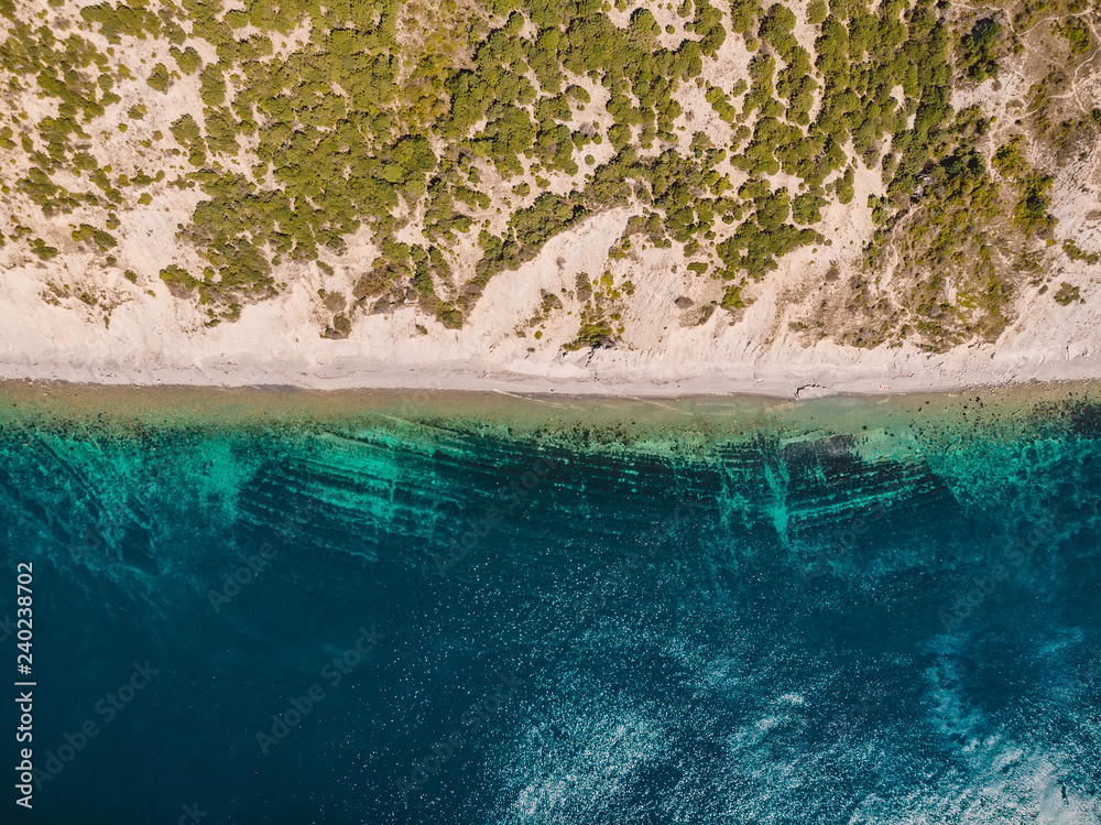 Sea coastline with cliff, trees and clear blue water from drone. Top view. Aerial view