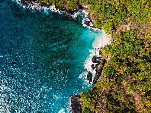Blue ocean in tropics with rocky coastline and little beach. Aerial view.