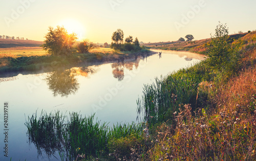 Sunny summer landscape with river flowing between the beautiful green hills,fields and meadows. 