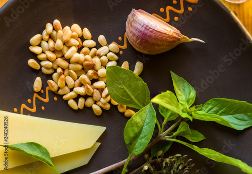 Fresh ingredients for preparing Italian pesto sauce - lemon basil sprigs, peeled seeds of cedar nuts, large garlic clove, Greek olive oil, Parmesan cheese photo