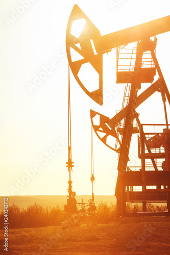 Pumping unit is working in oil field on the sunset background